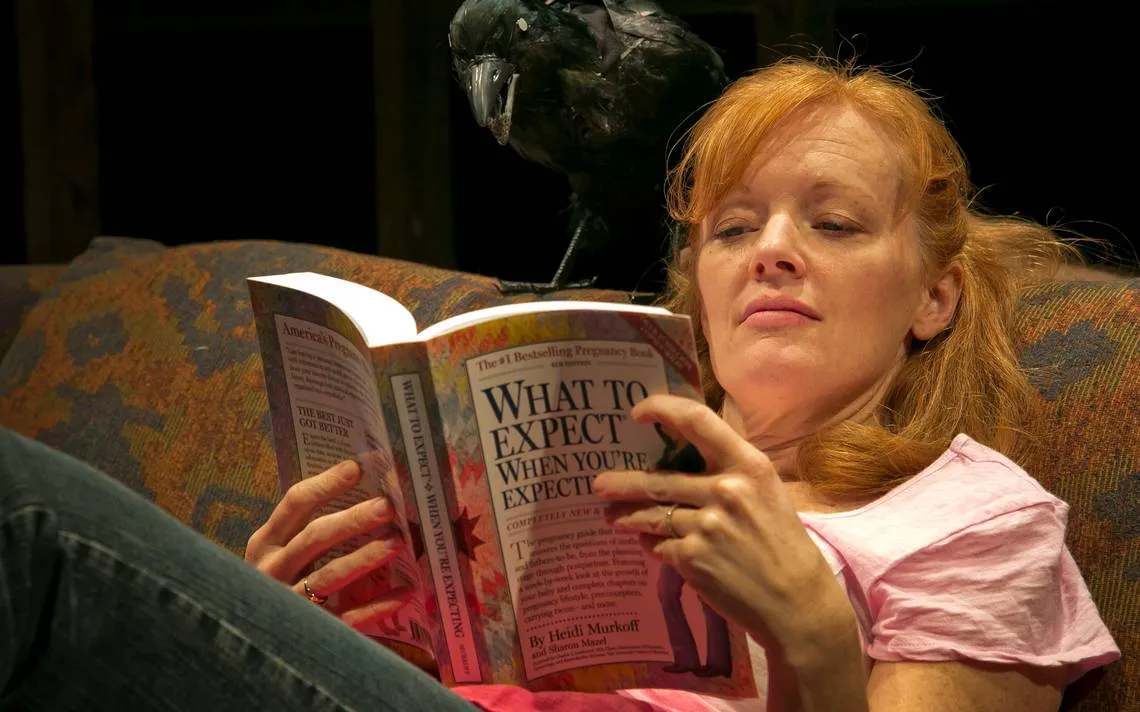 woman reading a book about birds on a couch.