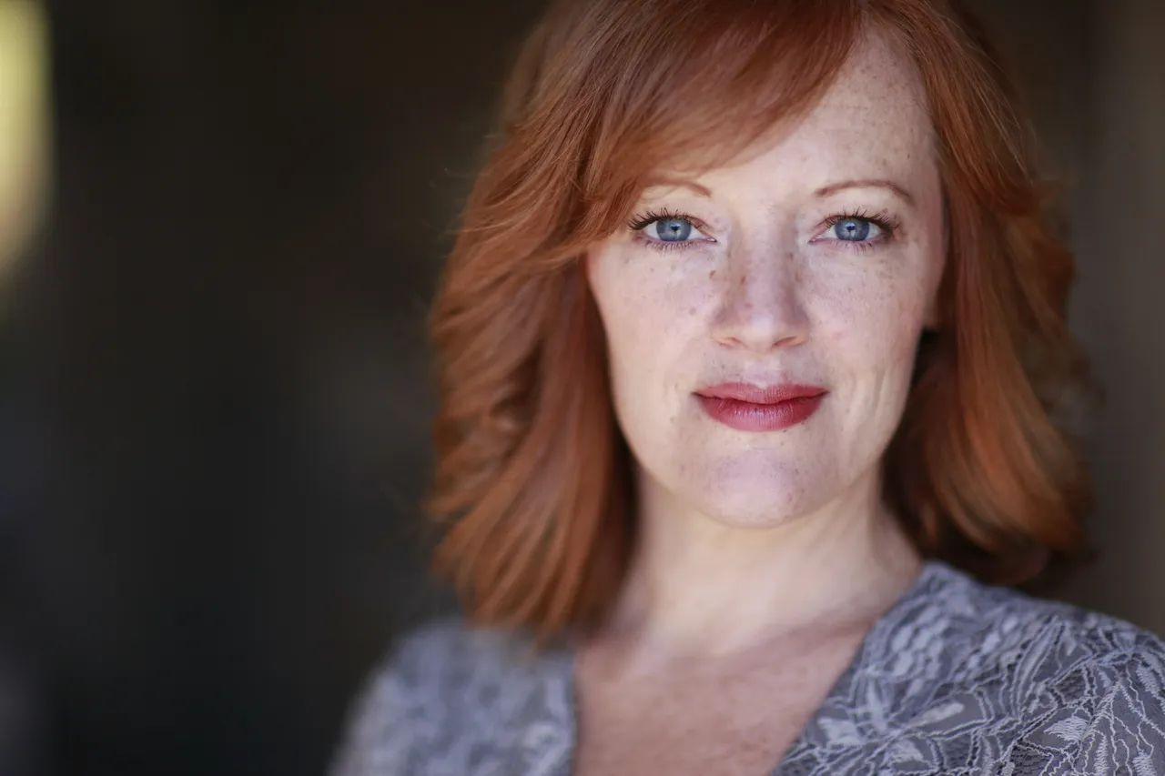 a blonde woman with blue eyes who is smiling at the camera.