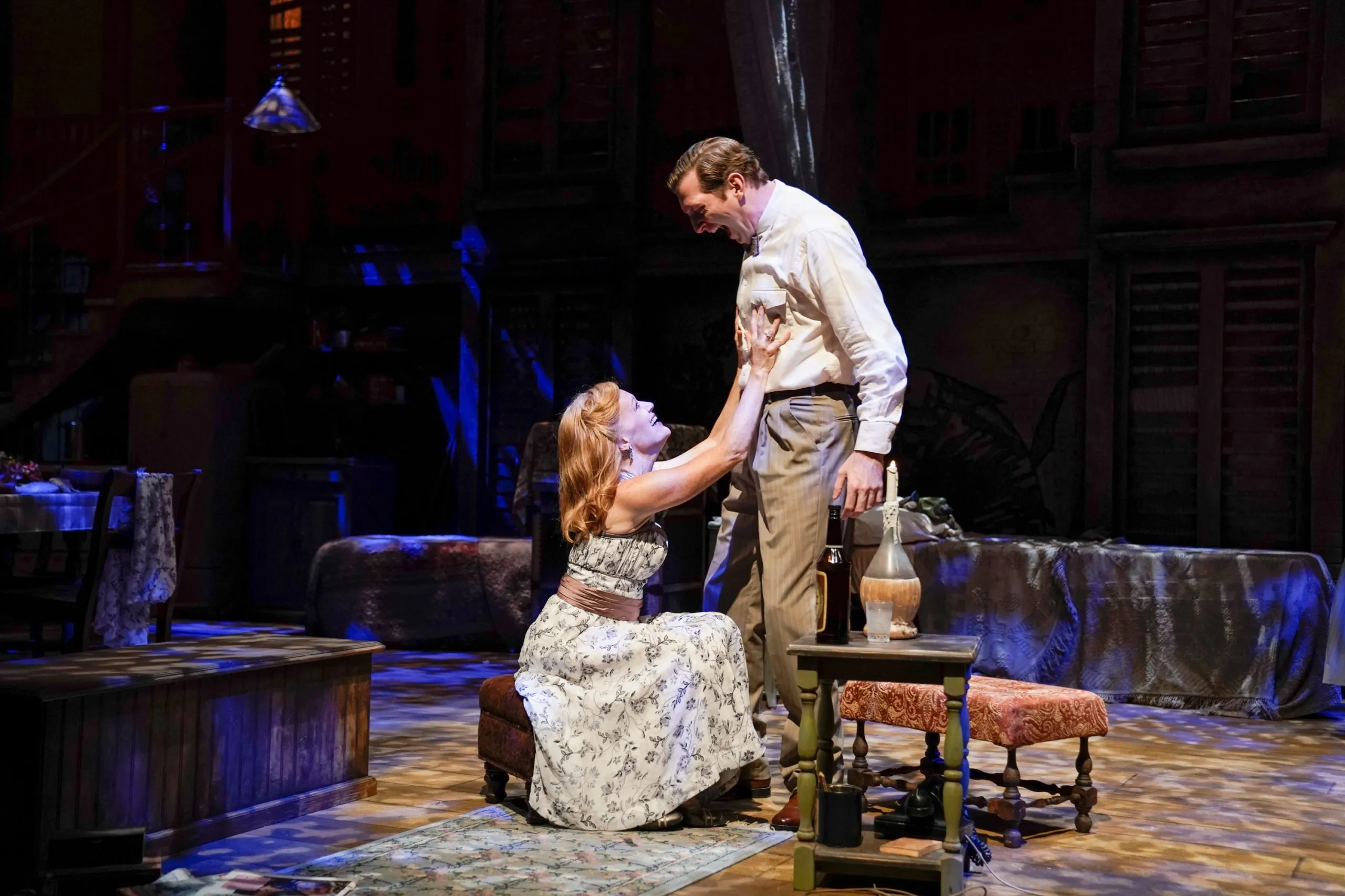 Men and women standing around a table with a lamp on it.